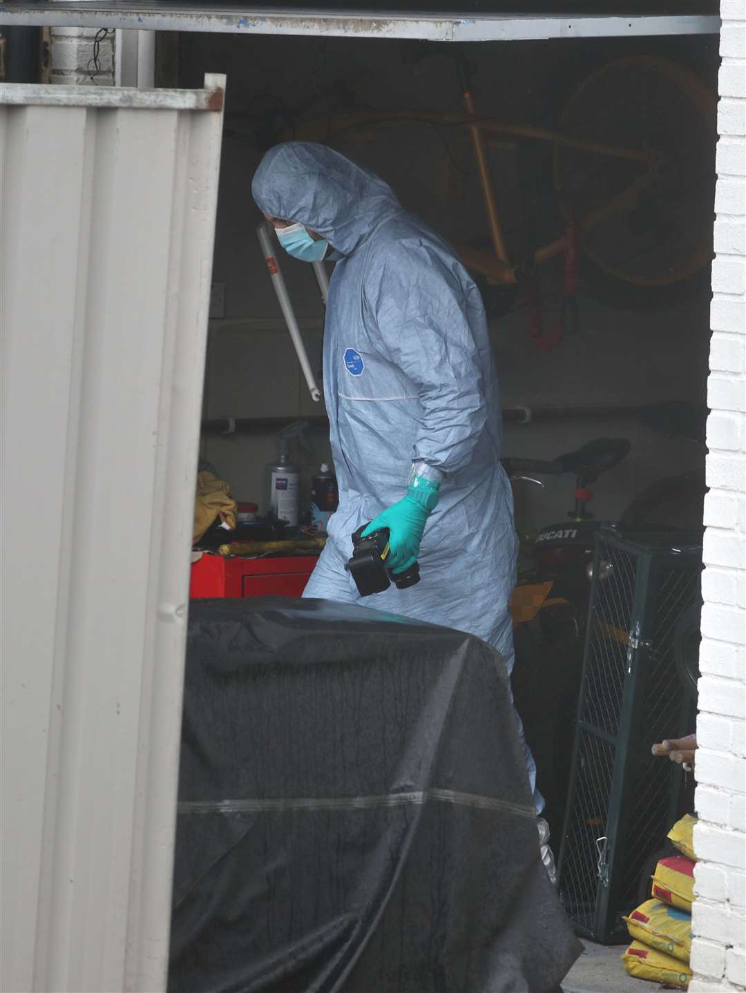 A forensic officer in a garage next to a house in Freemens Way in Deal (Steve Parsons/PA)