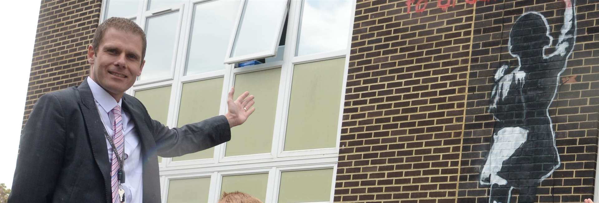 Darren Webb proudly revealing a mural which had been painted on the side of Loose Primary School in April