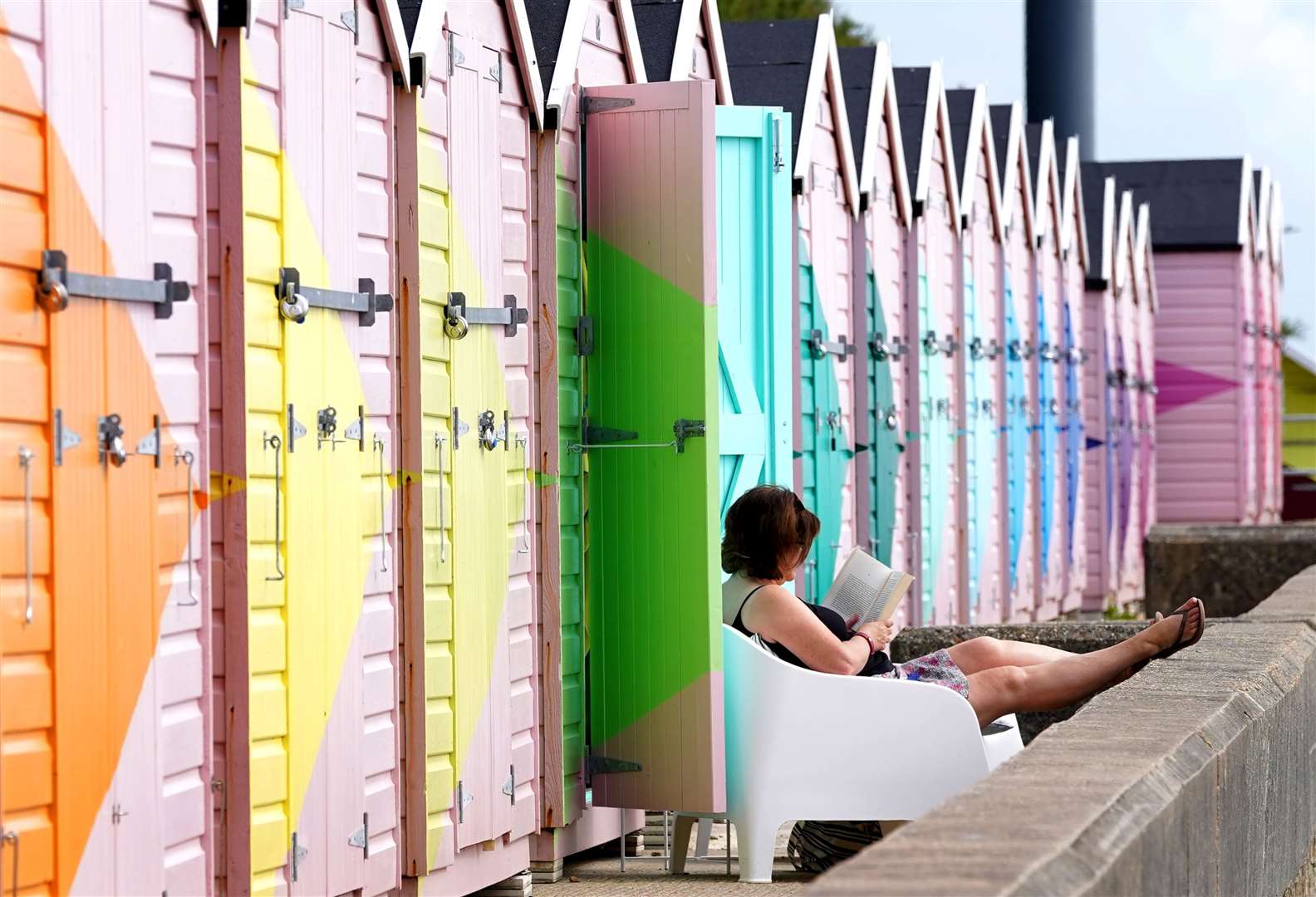 A lady enjoys her newly refurbished beach hut during the fine weather in Folkestone, Kent (Gareth Fuller/PA)