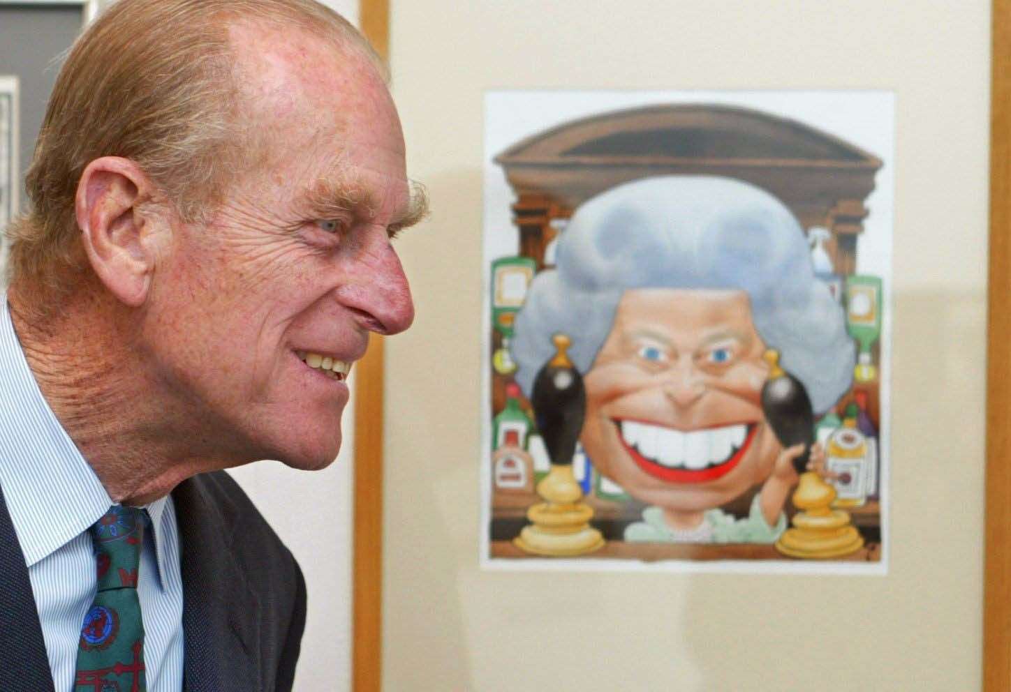 The Duke of Edinburgh next to a cartoon of the Queen standing behind the bar at the Old Vic pub from EastEnders at an exhibition (PA)