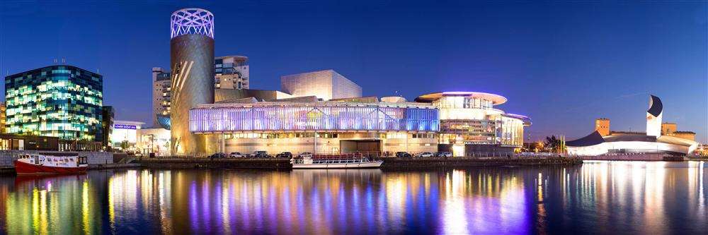 An overview of the Manchester Quays area at night, showing the Manchester Cruises boat on the far left, and the Lowry gallery in the middle, plus the Ship Canal