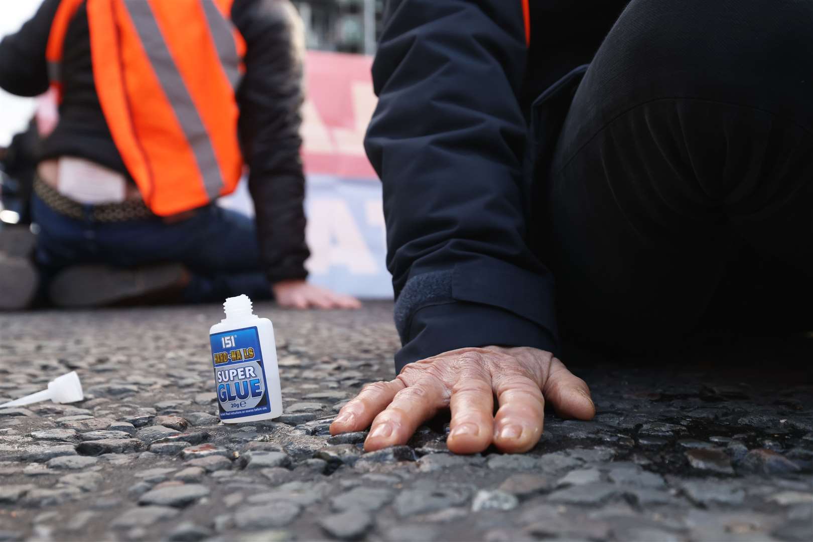 A protester with their hand glued to the road (James Manning/PA)