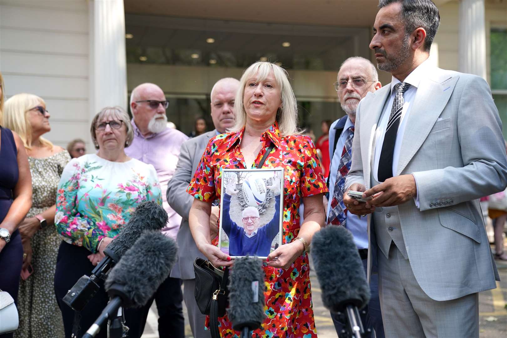 Anna-Louise Marsh-Rees, of Covid-19 Bereaved Families for Justice Cymru, holds a picture of her father as she speaks outside the inquiry in London (Lucy North/PA)