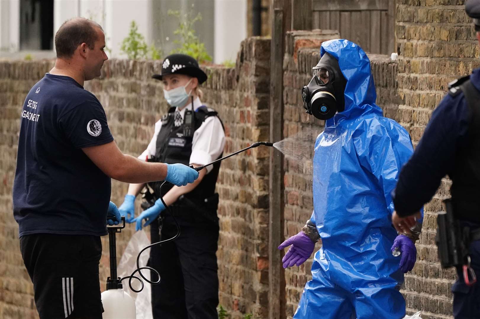 A police officer in a bio-hazard suit and breathing apparatus is sprayed down by a member of the Territorial Support Group (TSG) (Aaron Chown/PA)