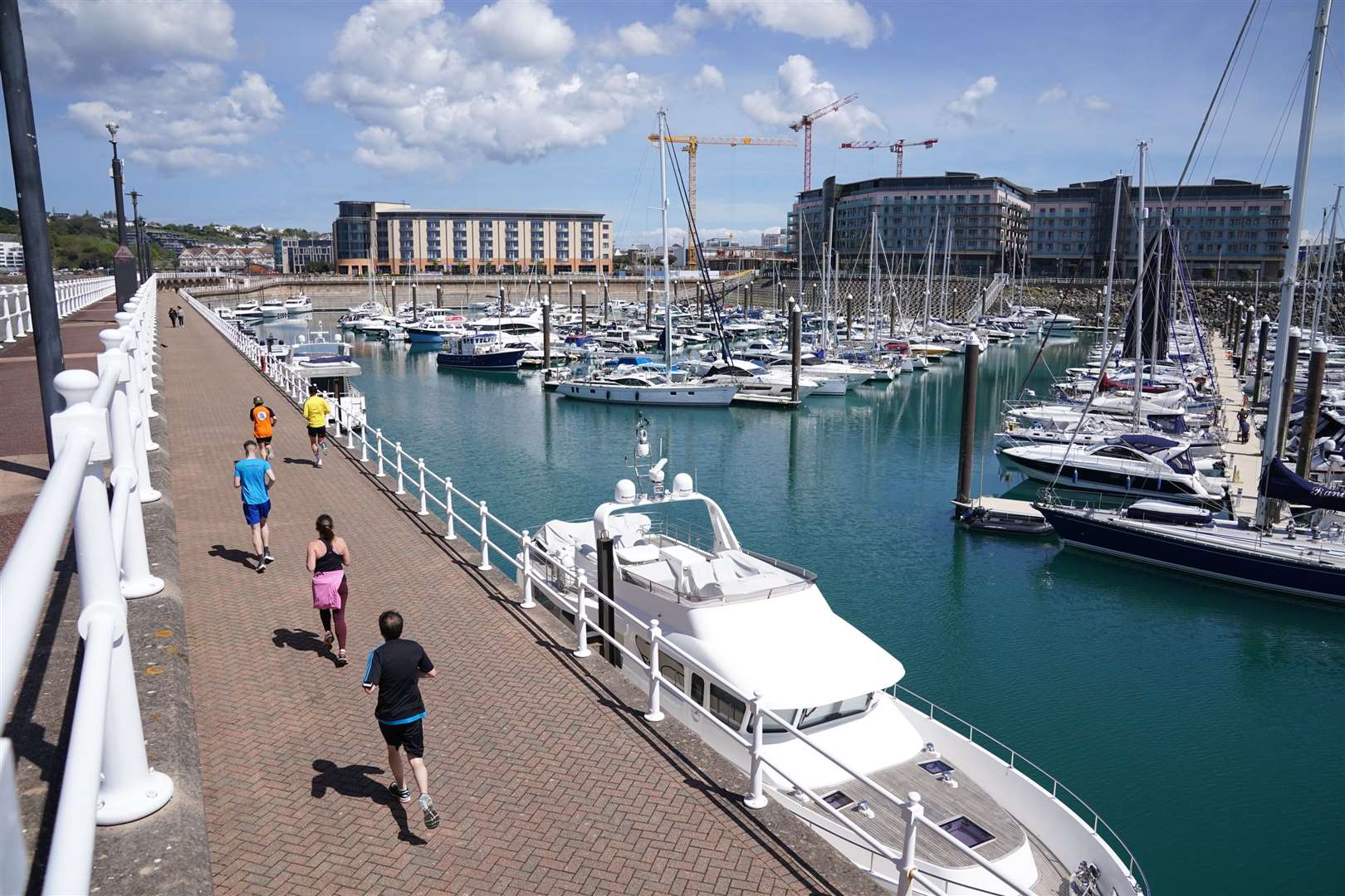 Joggers run past boats near to the harbour at St Helier (Aaron Chown/PA) 