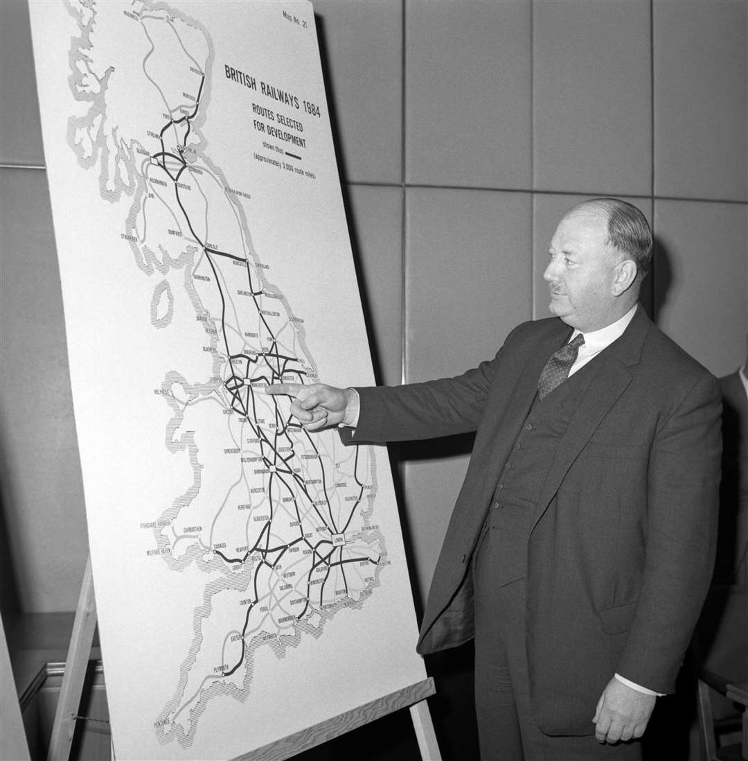 Richard Beeching looking at a large map, showing how British Rail trunk routes might look in 1984 (PA)