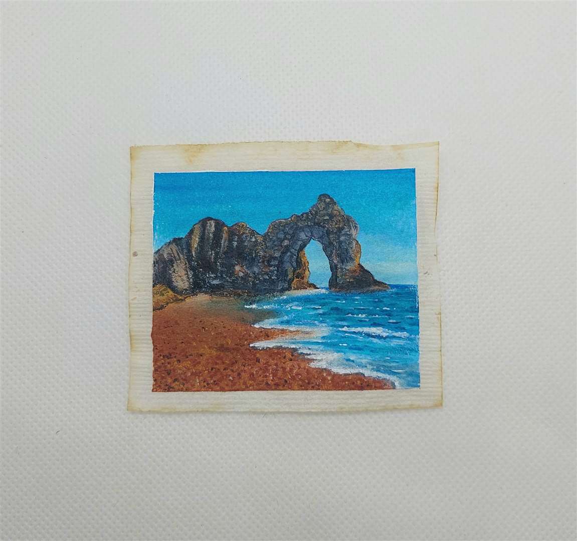 Caroline West’s painting of Durdle Door on a used tea bag (Caroline West/PA)