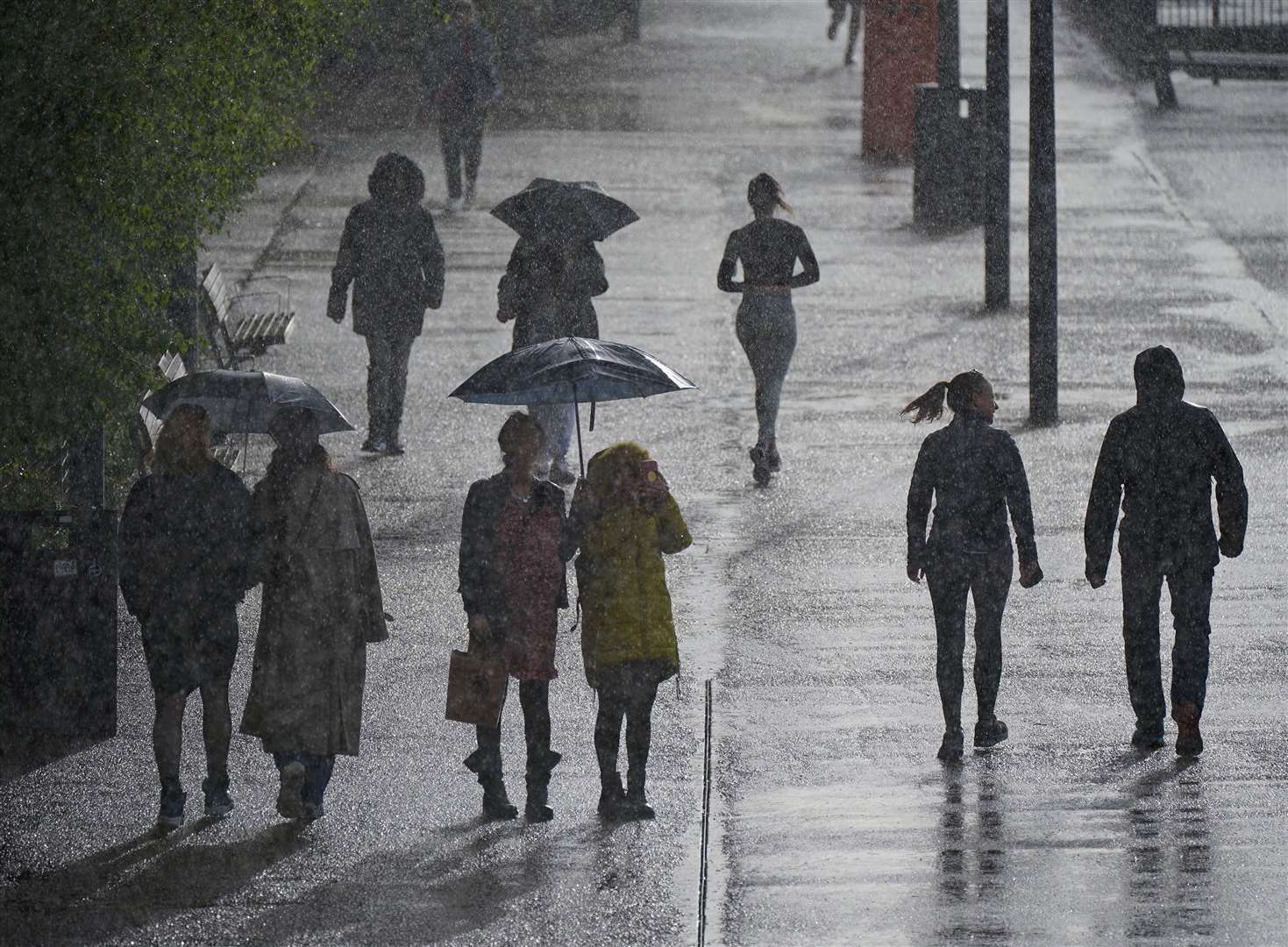 People are caught in a rain shower (Yui Mok/PA)