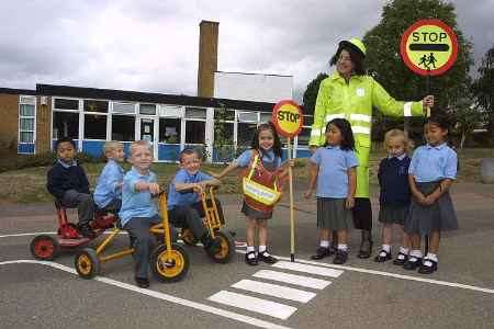 Teacher Jill Haslam and pupil Leila Santos act as"lollipop ladies" to help youngsters cross the road. Picture: JOHN WESTHROP