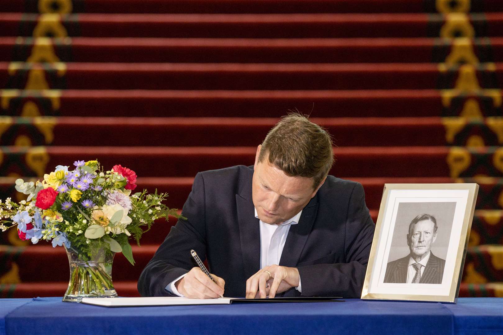 SDLP councillor Donal Lyons signs a book of condolence opened at Belfast City Hall for Lord David Trimble (Liam McBurney/PA)