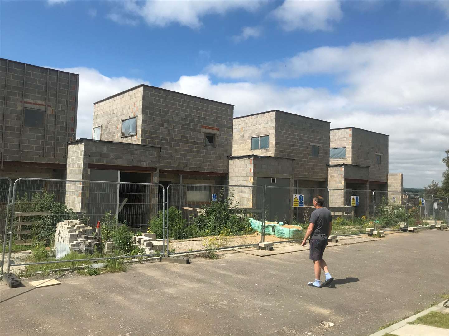 Mark outside some of the derelict unfinished houses opposite his home