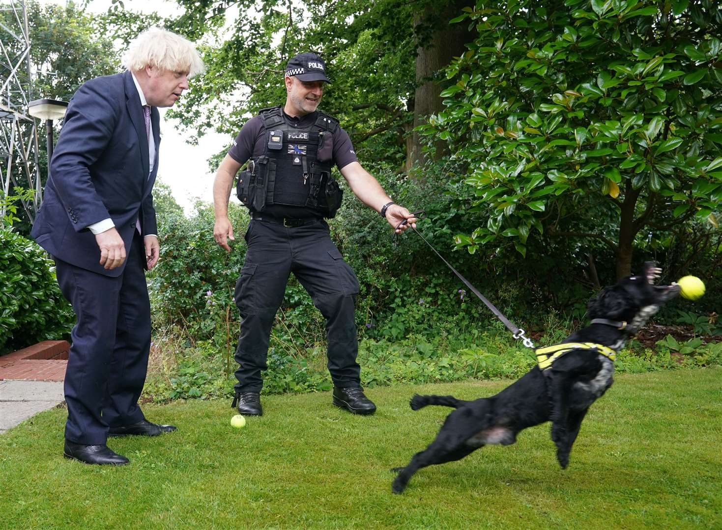 Prime Minister Boris Johnson speaks to Sergeant Dog Handler Mike Barnes as he throws a ball for six-year-old cocker spaniel Rebel (Yui Mok/PA)