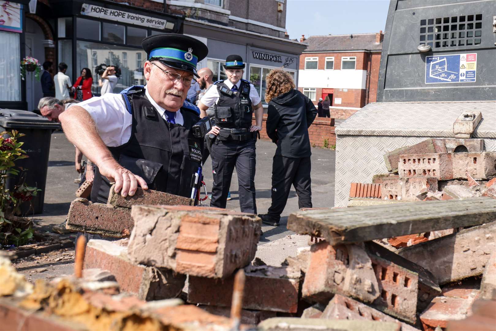 A police community support officer removes bricks from a damaged wall on Sussex Road in Southport (James Speakman/PA)