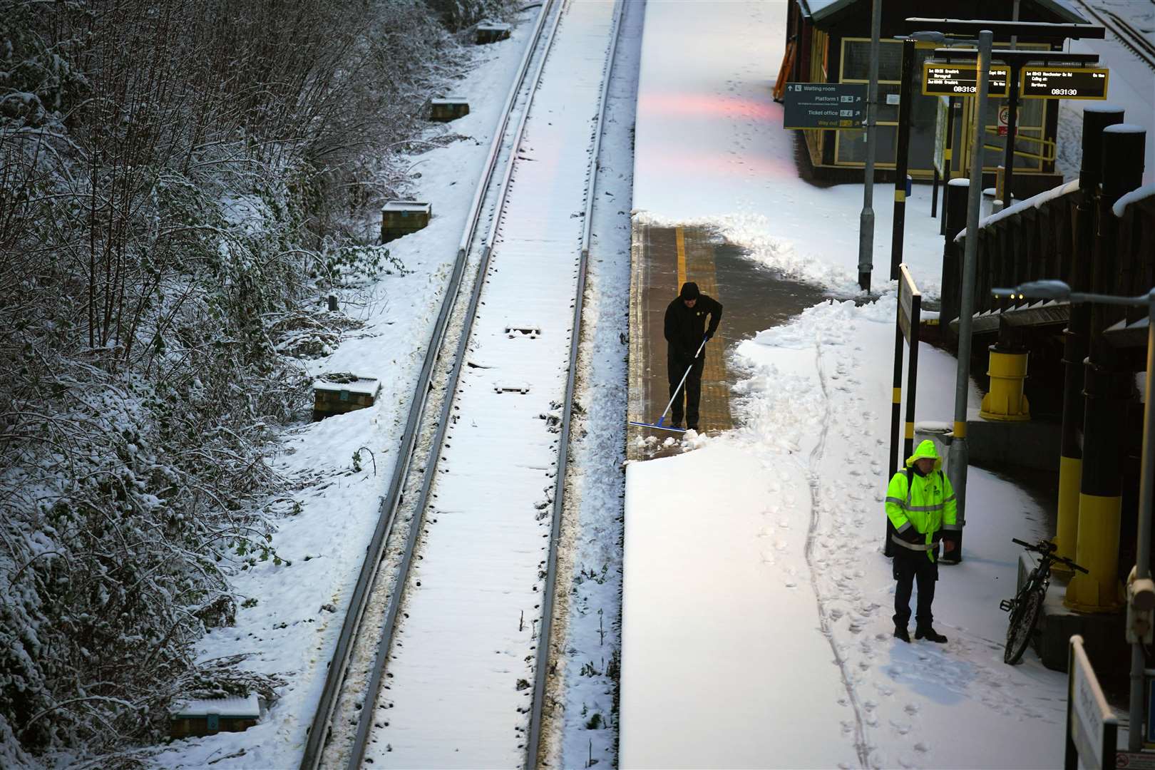 A worker clears snow from the platform at Hunt’s Cross station in Liverpool (Peter Byrne/PA)