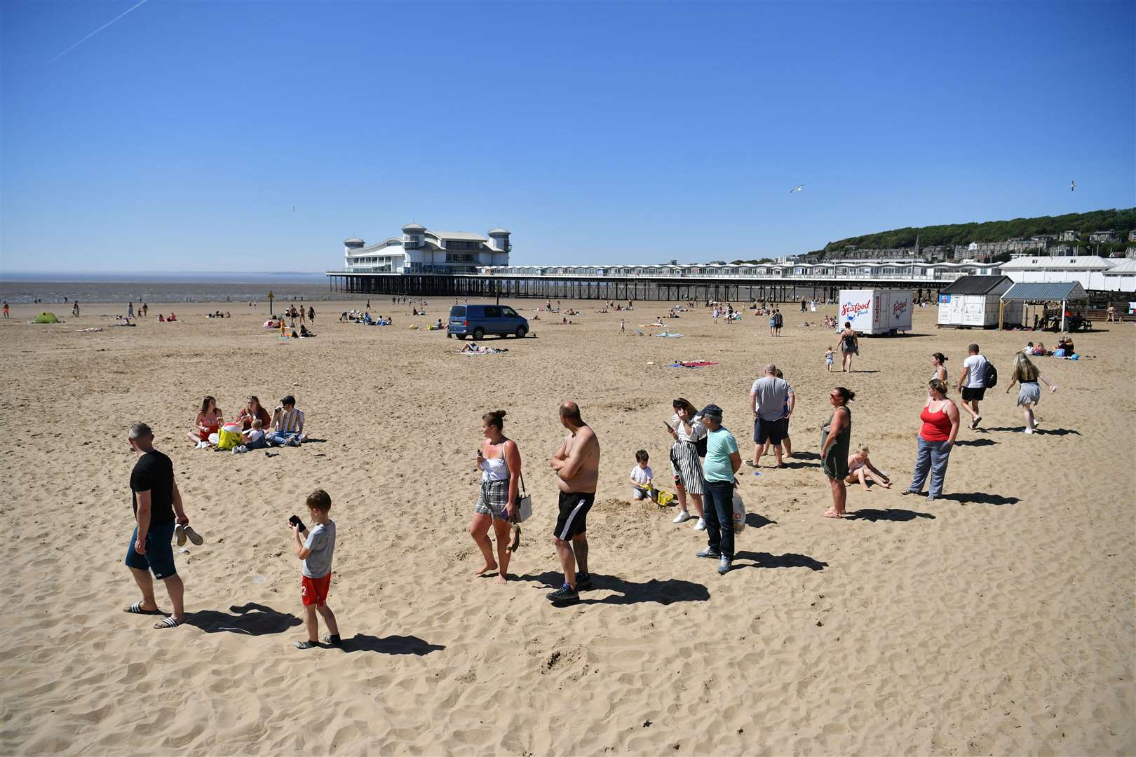 Sunbathers social distancing as they queue for ice cream in Weston-super-Mare (Ben Birchall/PA)