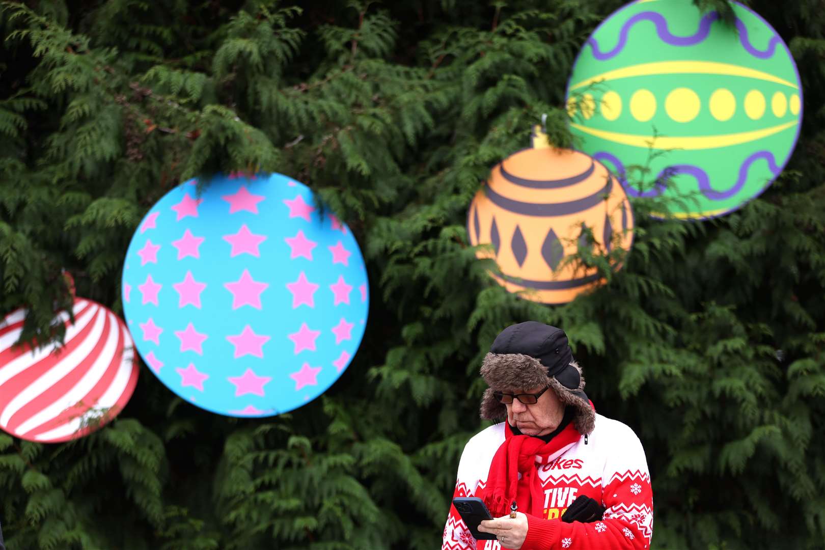 A man checks the odds in front of a tree festooned with giant decorations at Kempton (Steve Paston for The Jockey Club/PA)