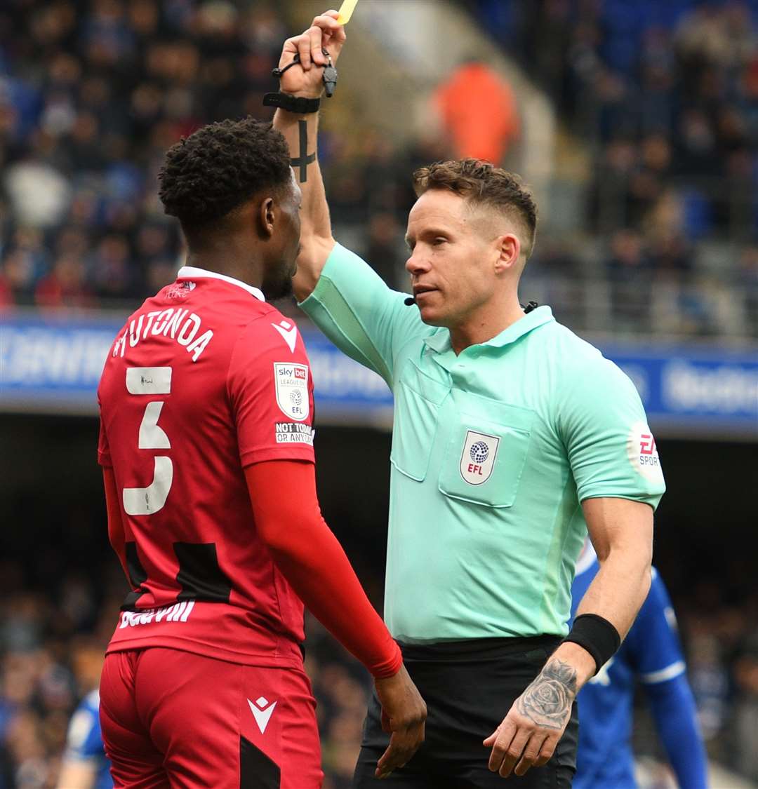 Gills' David Tutonda is given a yellow card by referee Stephen Martin. Picture: Barry Goodwin