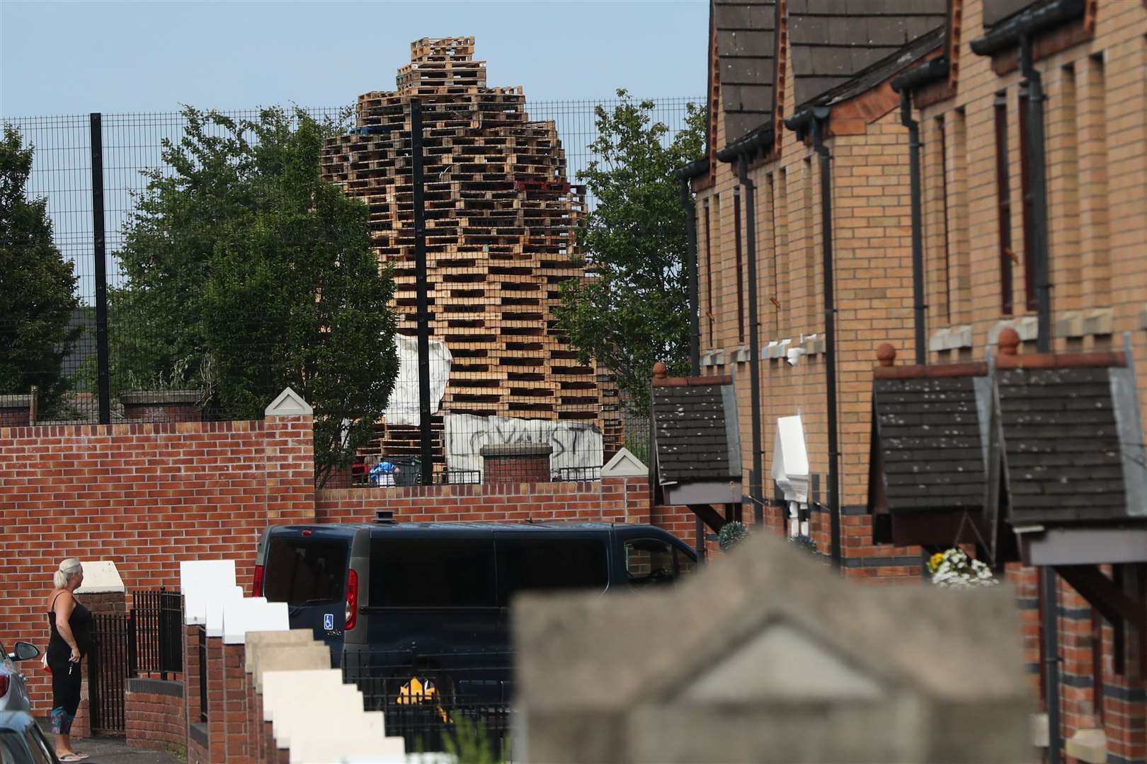 A woman looks at the controversial loyalist bonfire, built in the loyalist Tiger’s Bay area, from nationalist New Lodge area in north Belfast (Niall Carson/PA)