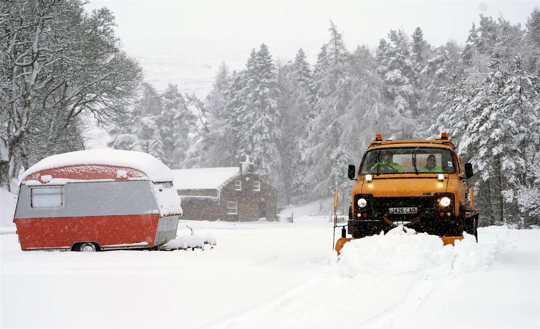 A snow plough passes an old caravan in Nenthead, Cumbria (Owen Humphreys/PA)