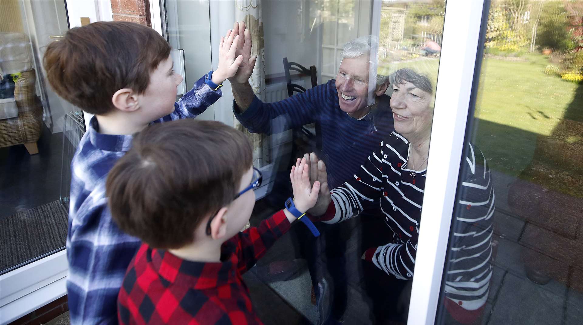 Ben and Isaac talk to their grandparents Sue and Alan through a window as they self-isolate at their home in Knutsford, Cheshire (Martin Rickett/PA)