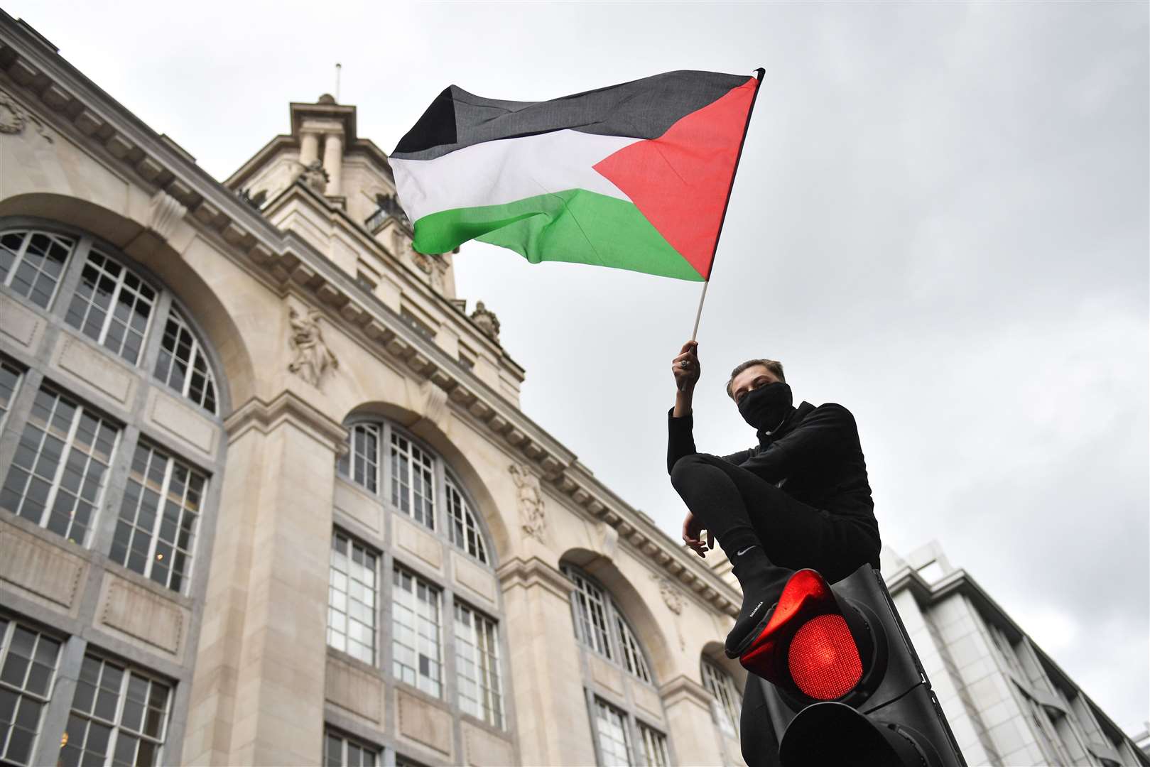 One demonstrator waving a Palestinian flag climbed on top of a traffic light (Dominic Lipinski/PA)