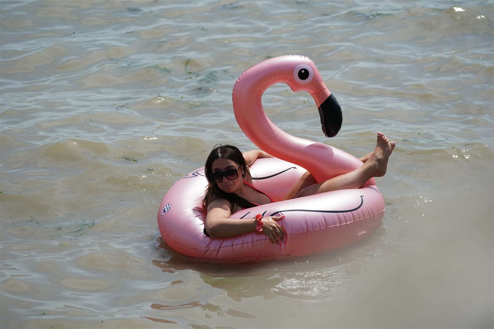 A beachgoer floats in a flamingo rubber ring in the sea at Southend-on-Sea (Yui Mok/PA)