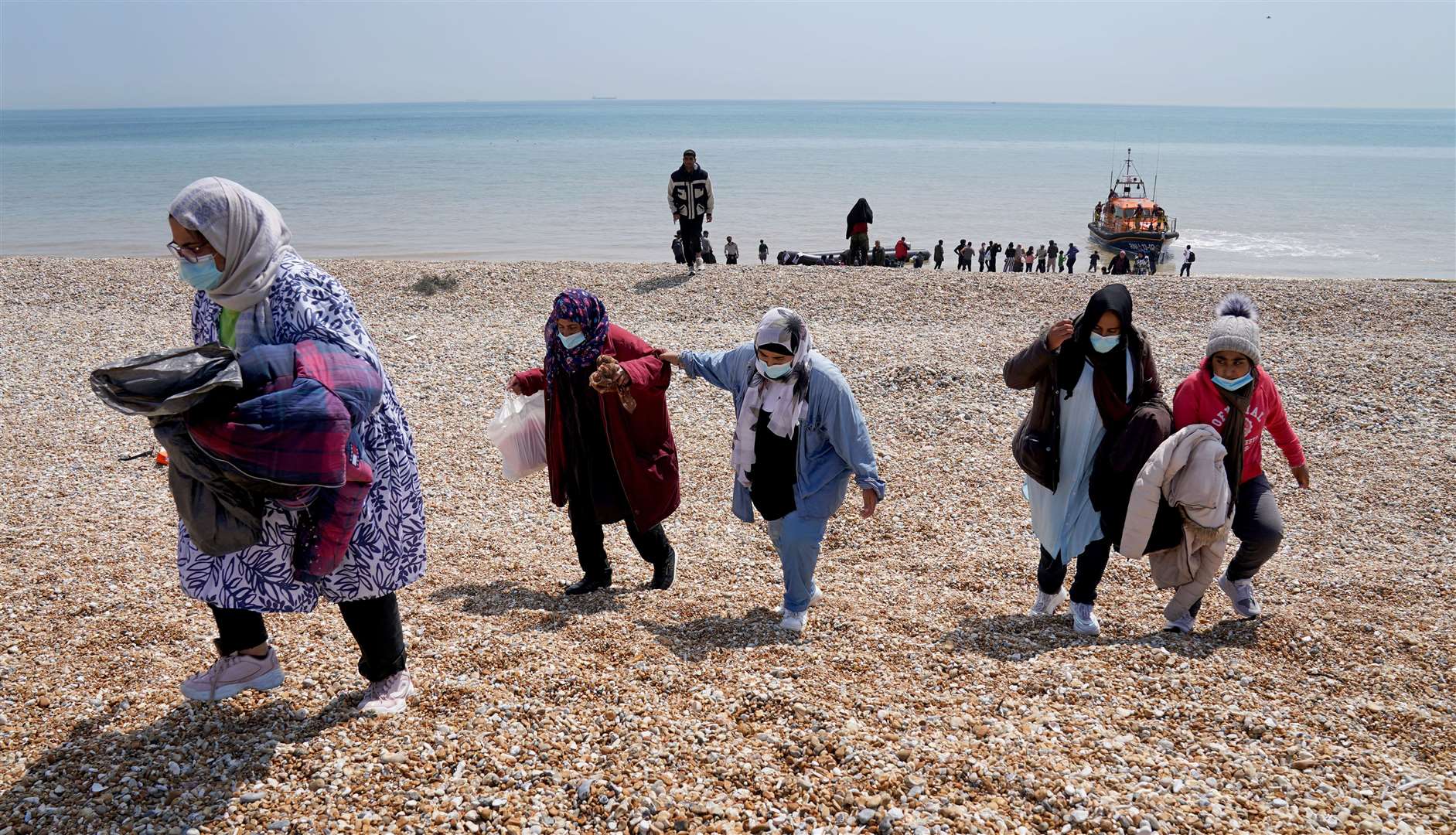 People thought to be migrants make their way up the beach after arriving on a small boat at Dungeness in Kent (Gareth Fuller/PA)