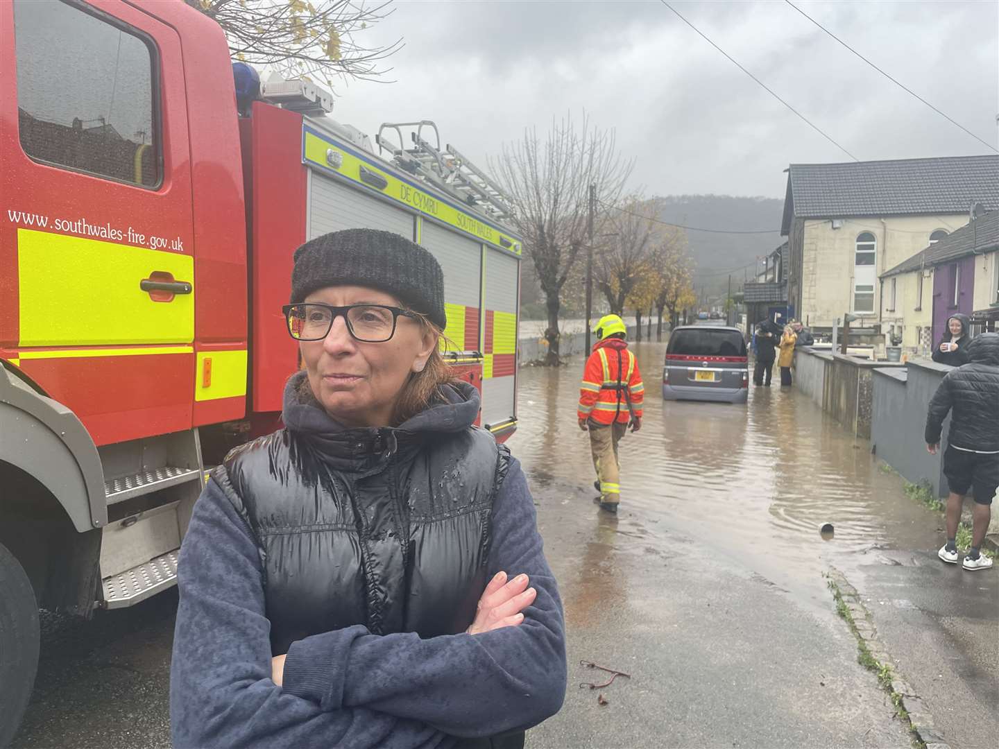 Resident Claire Instrell, whose home appears to have avoided being flooded but experienced it four years ago, watches proceedings on Sion Street, in Pontypridd, Wales (George Thompson/PA)