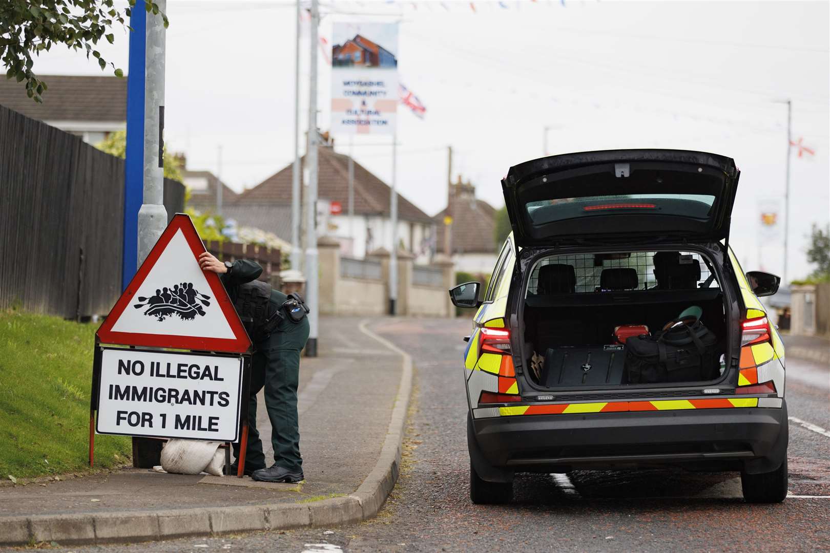 PSNI officer on Monday removing a road sign with image of people a dingy boat with the message, ‘No illegal immigrants for 1 mile’, erected close to the Orange Arch in Moygashel, Co Tyrone (Liam McBurney/PA)