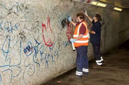 Volunteers at work cleaning graffiti in a subway