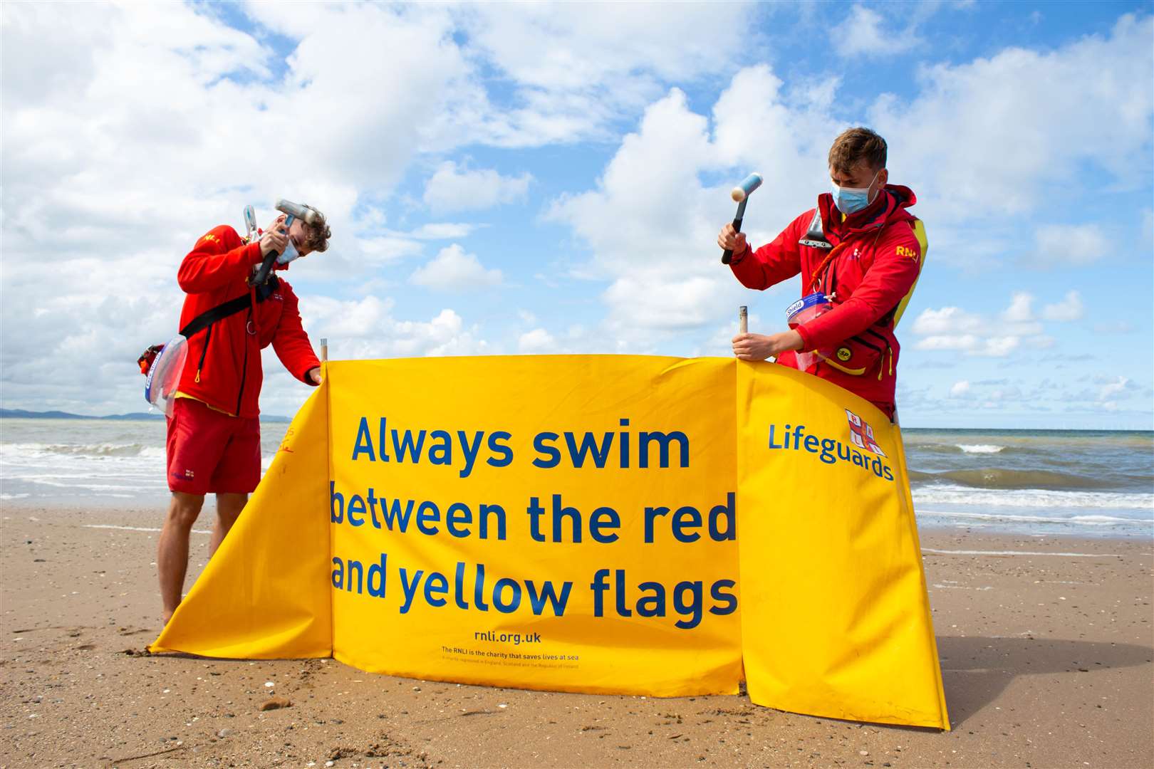 Lifeguards George Davies and Matty Jones offer advice to swimmers in Rhyl (Nathan Williams/RNLI)