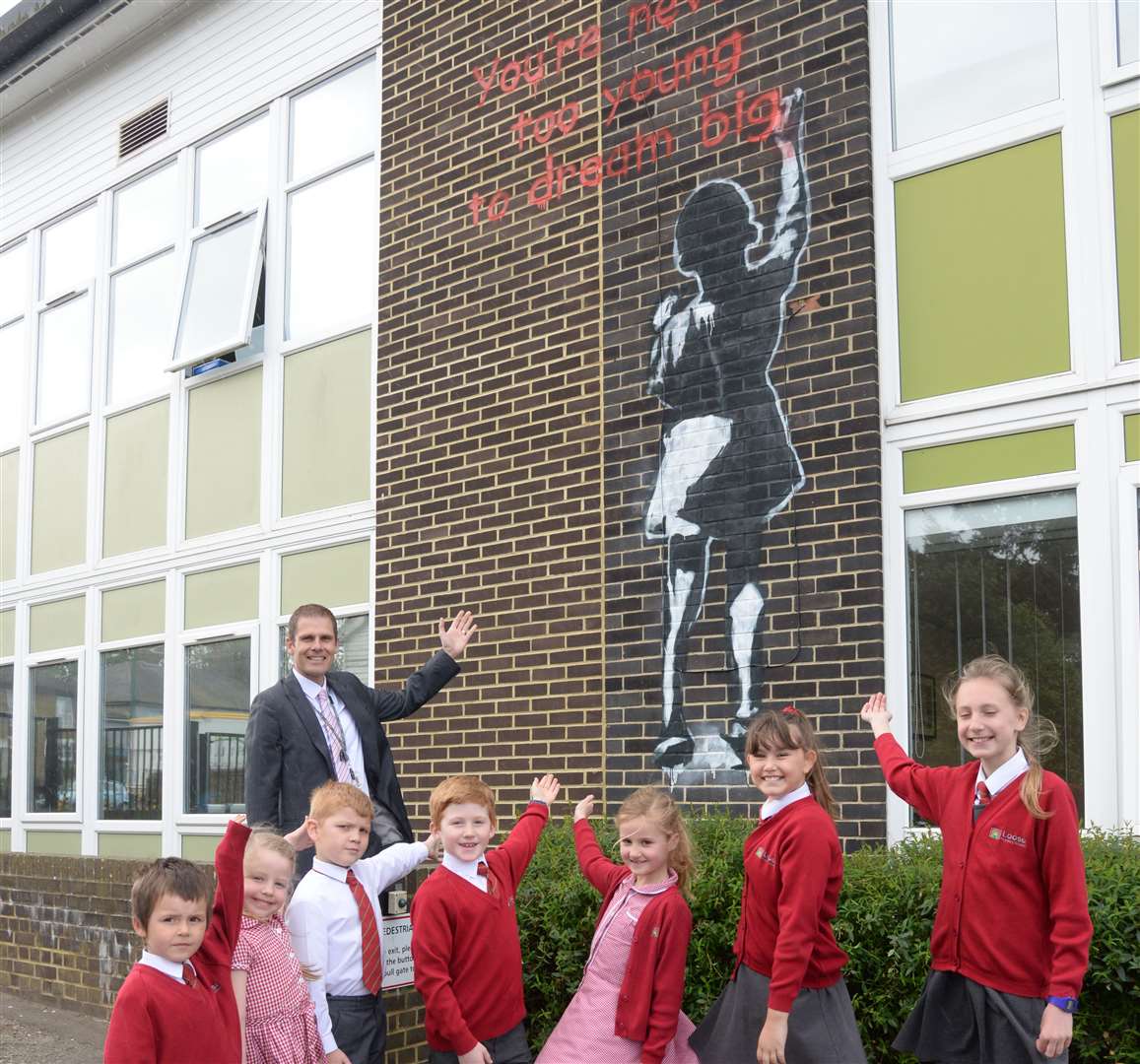Darren Webb, Executive Head with some of his pupils and the Banksy style graffiti at Loose Primary School on Wednesday. Picture: Chris Davey. (9080206)