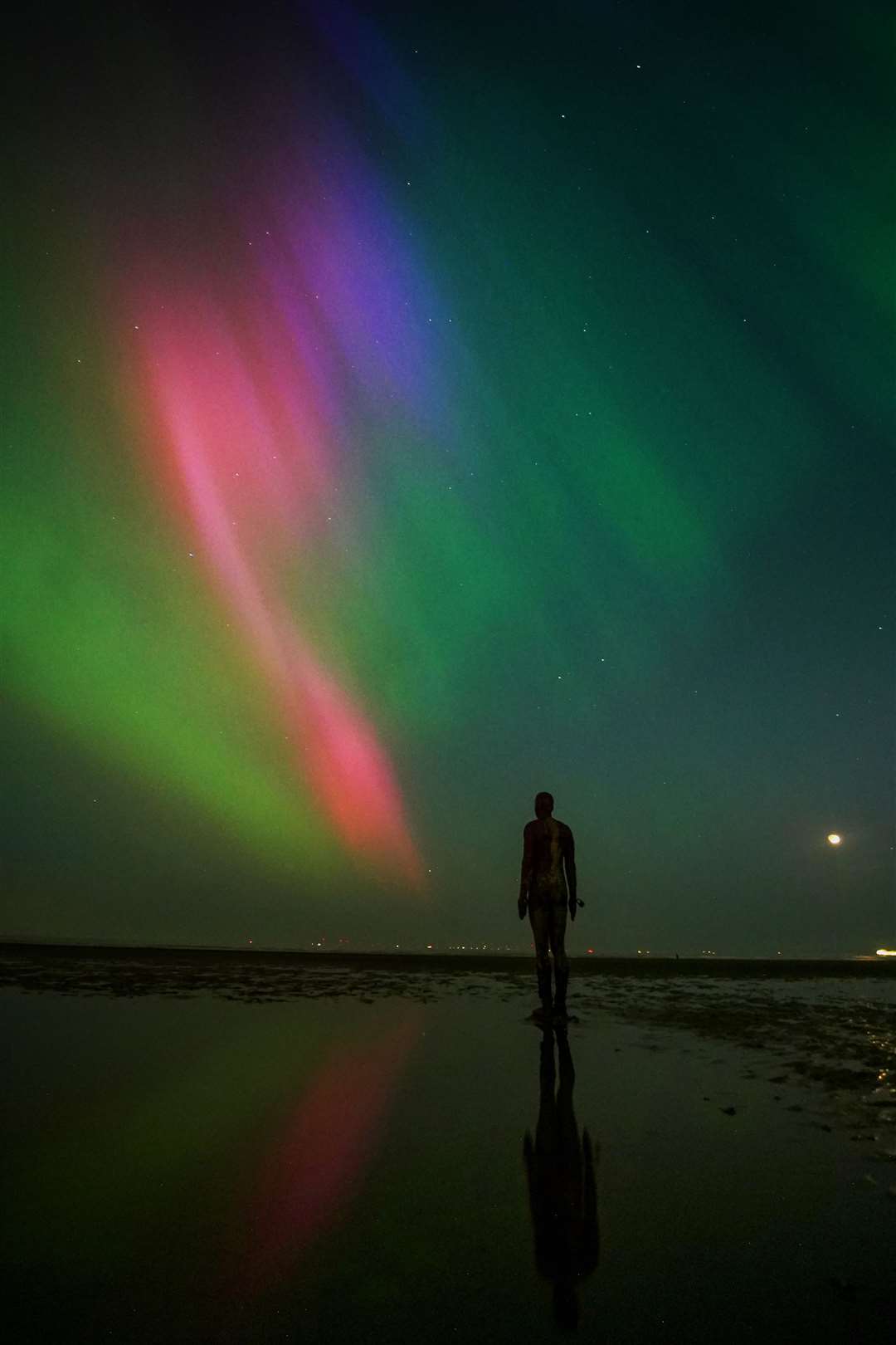 The Northern lights glow on the horizon above sculptures on Crosby Beach, Merseyside (Peter Byrne/PA)