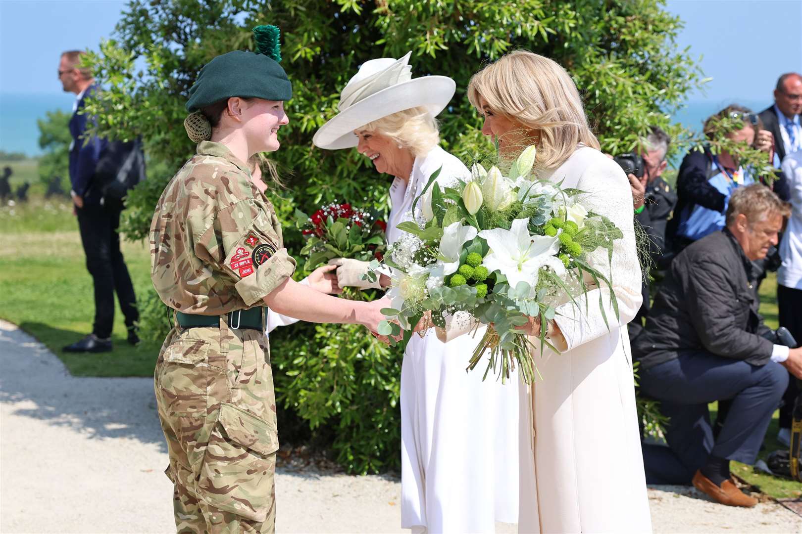 The Queen and Brigitte Macron receive bouquets to lay at the French Memorial in Ver-sur-Mer (Chris Jackson/PA)