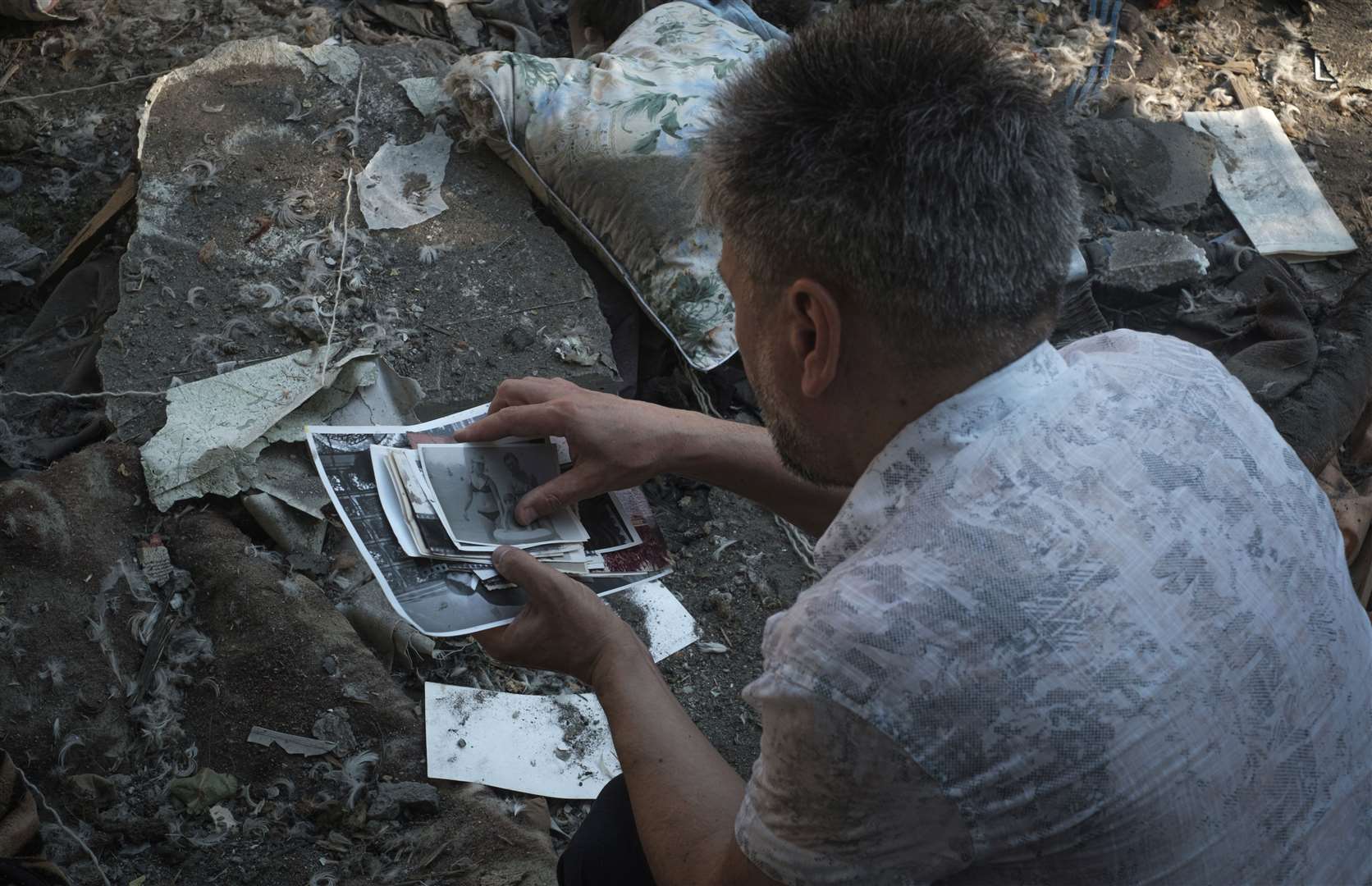 A local resident collects photos of his family left under the rubble after Russian shelling in Mykolaiv, Ukraine (George Ivanchenko/AP)