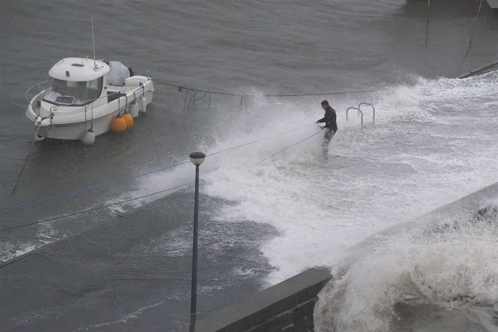 A man ties up his boat at Stonehaven at the start of Storm Babet (Andrew Milligan/PA)