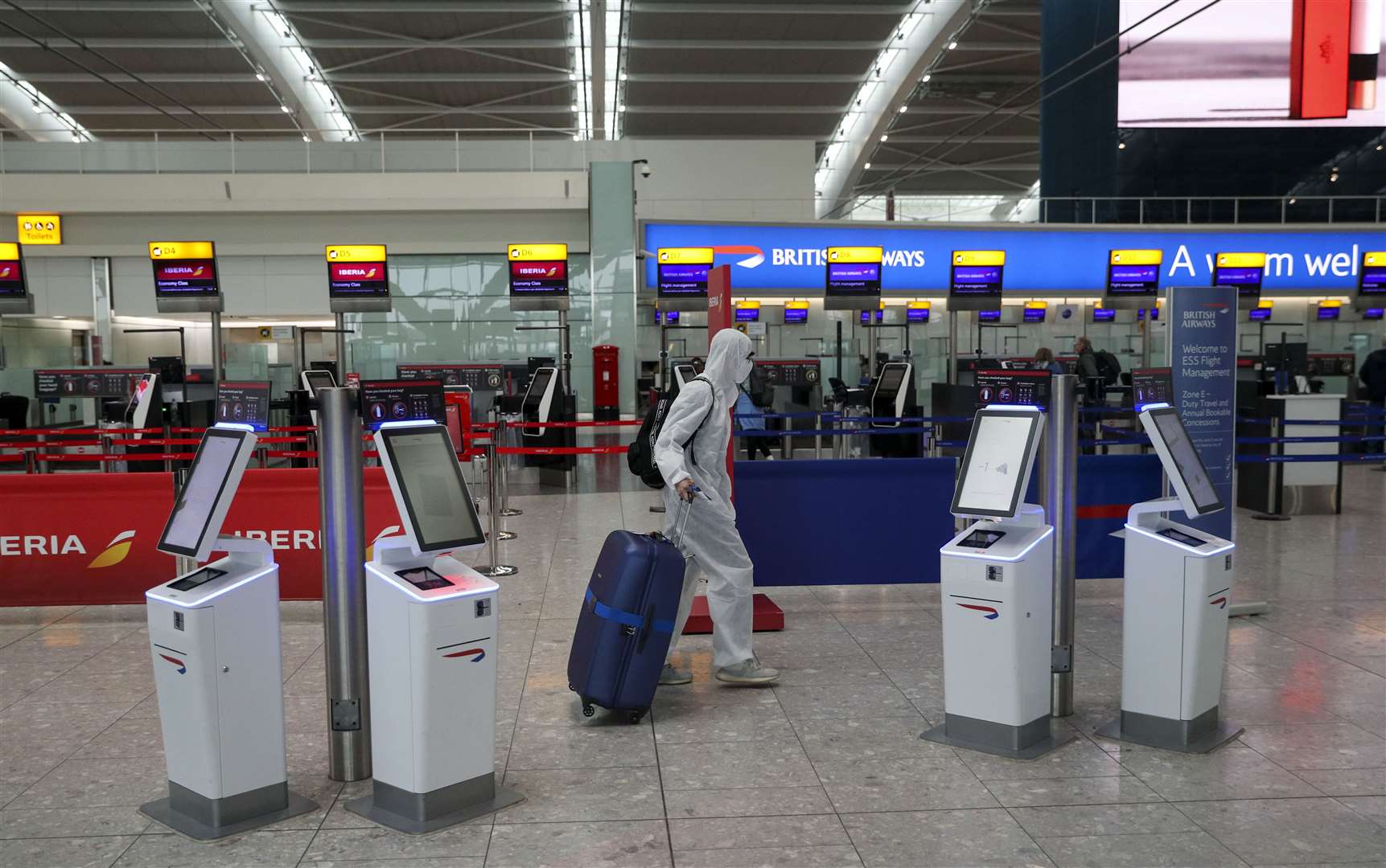 A passenger wearing protective clothing checks in for a flight from Heathrow Airport’s Terminal 5 in London.