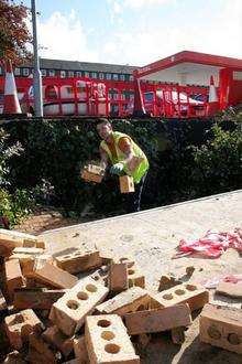 A construction worker fixes a wall at the Total garage in Dock Road, Chatham, after a woman in her 80s crashed her car over the wall.