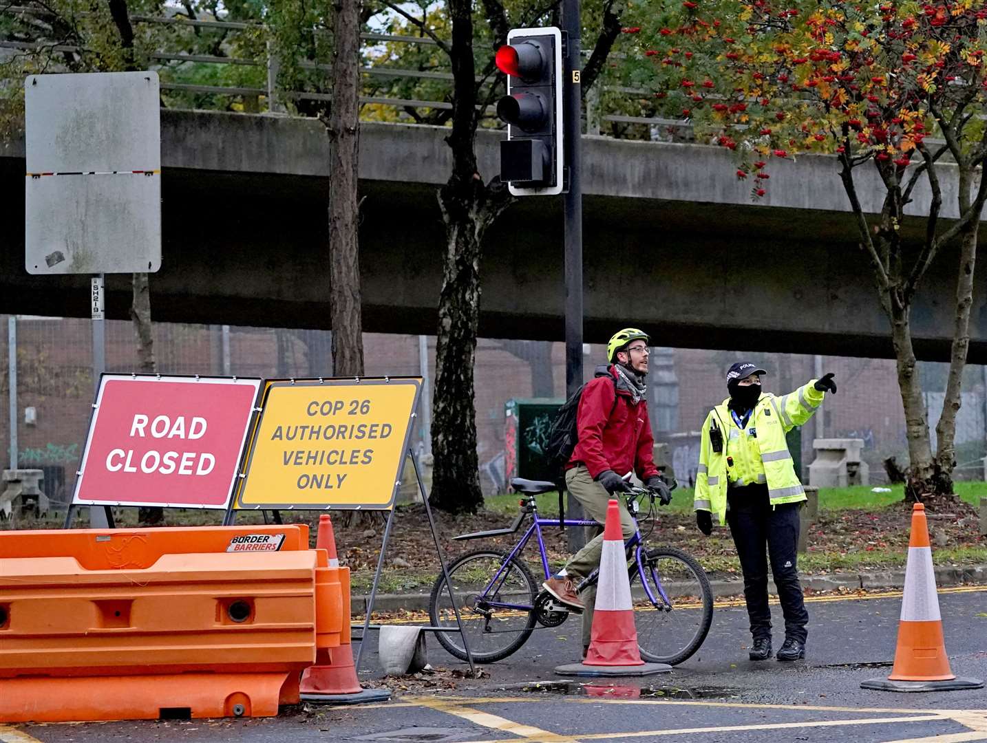 A police officer gives directions to a cyclist away from the roadblock at the entrance to the Clydeside Express in the centre of Glasgow (Andrew Milligan/PA)