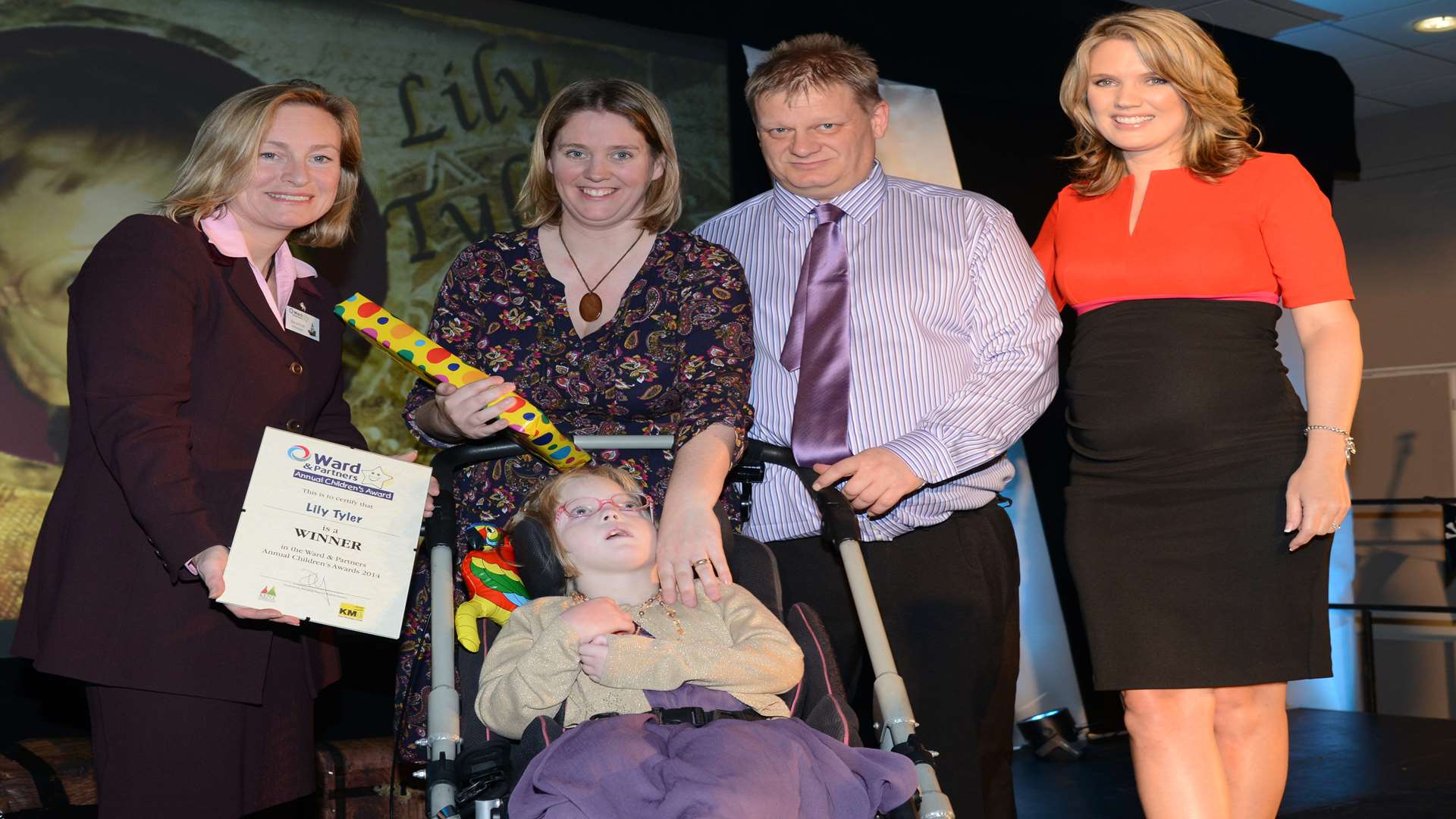 Lily Tyler who won last year’s Triumph Over Adversity Award with mum Andrena and dad Jonathan, presented by KM Group chairman, Geraldine Allinson and TV presenter, Charlotte Hawkins