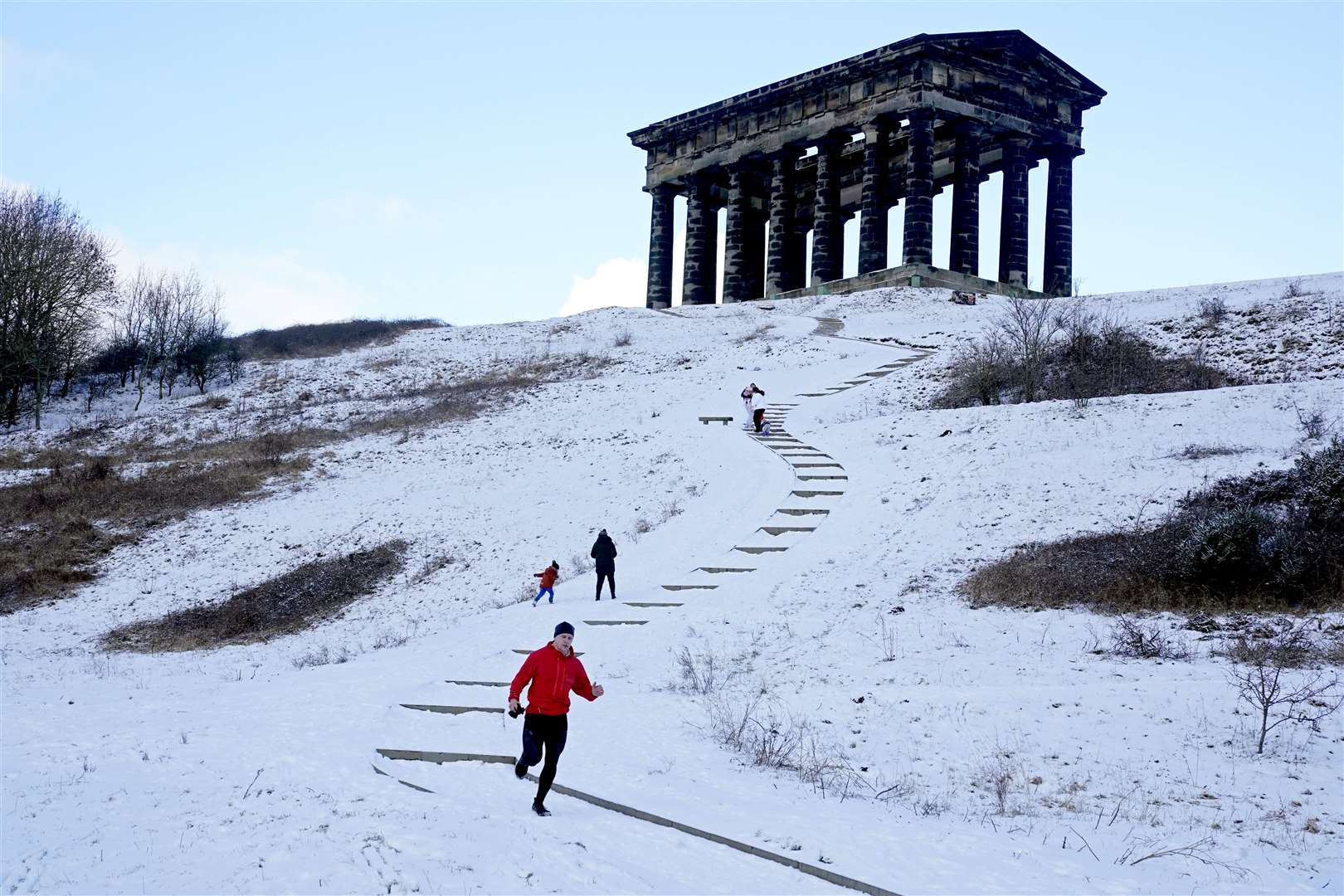 Sledgers and joggers traverse the steps to the Penshaw Monument on Penshaw Hill, Sunderland (Owen Humphreys/PA)