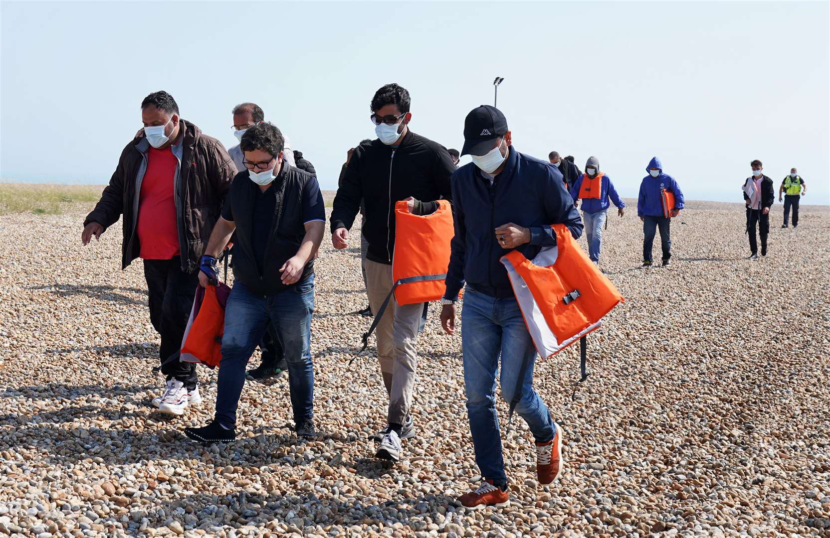 A group of people thought to be migrants crossing from France are escortedfrom the beach at Dungeness, Kent, by officials (Gareth Fuller/PA)