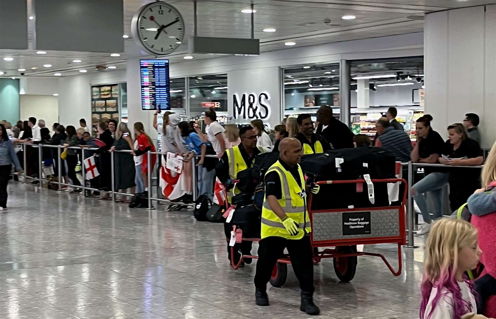 Airport staff with luggage pass through arrivals (Andrew Matthews/PA)