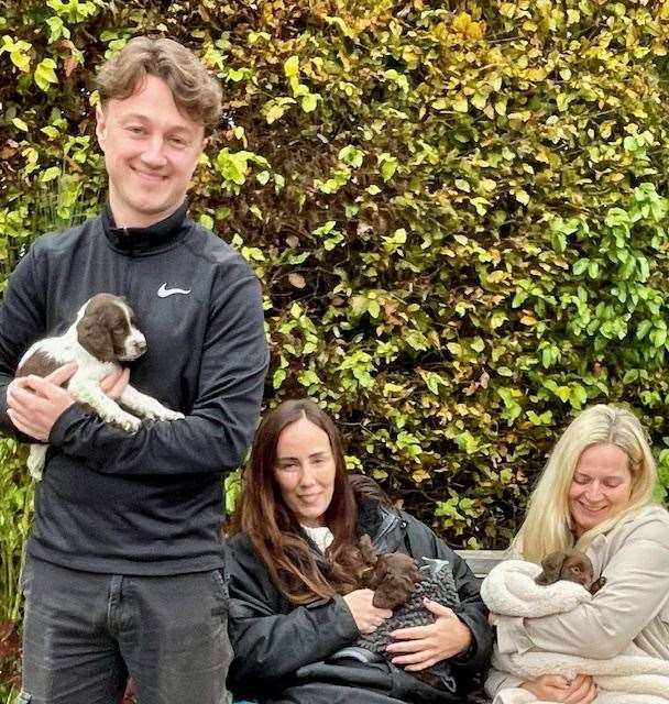 New owners cuddle their spaniel pups from the Lord Whisky Animal Sanctuary