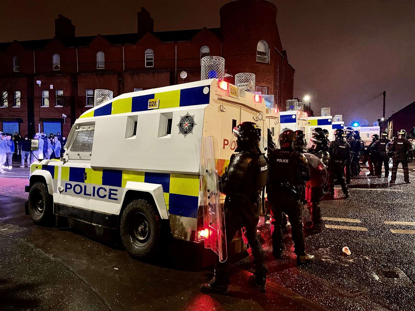 PSNI officers and Land Rovers on the nationalist side of the Springfield Road in Belfast after dispersing people from the area (Liam McBurney/PA)