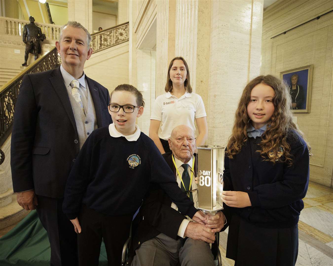 George Horner holds the D-Day 80 Torch of Commemoration with Mason and Sophie from Forge Integrated Primary School and Assembly Speaker Edwin Poots (left) in the Great Hall at Parliament Buildings (Liam McBurney/PA)