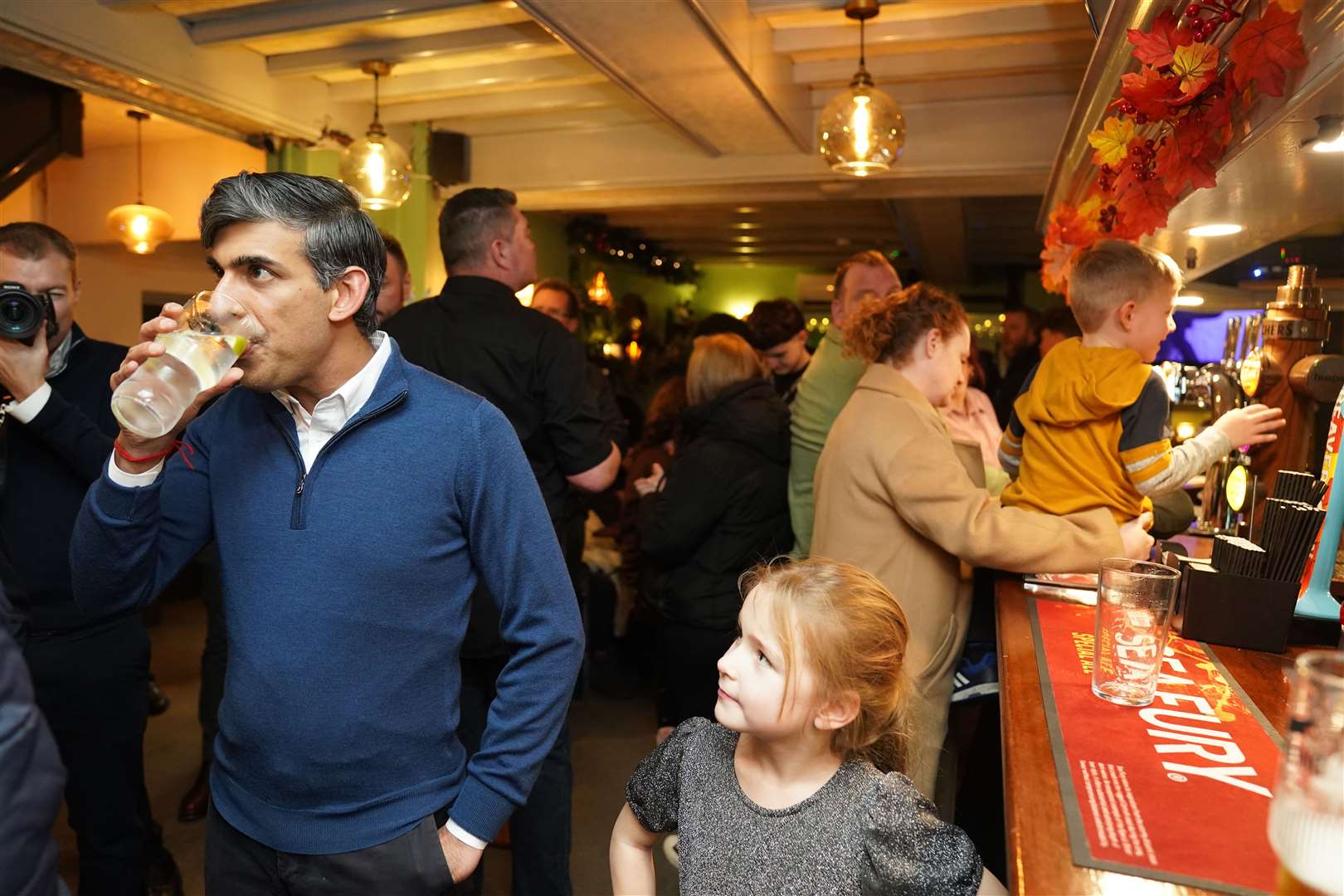 A future voter keeps an eye on Rishi Sunak as he enjoys a drink during a visit to a pub in Glossop, Derbyshire (Jacob King/PA)