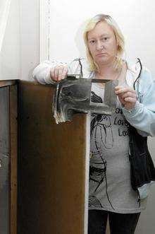 L-R Karen Bennett with the melted fuse box cover next to the cupboard under the stairs where it all started.