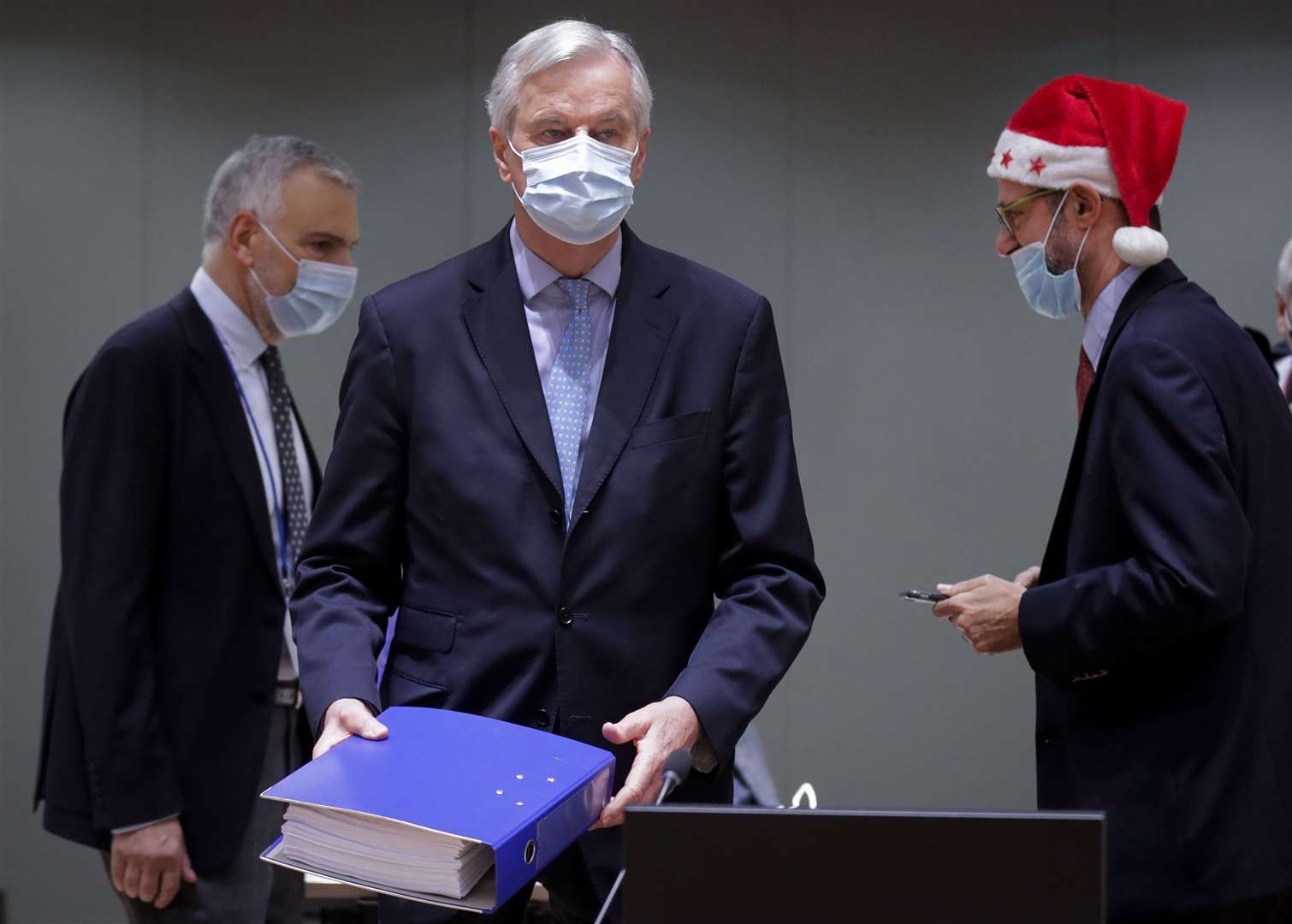 Michel Barnier, centre, carries a binder of the Brexit trade deal during a special meeting at the European Council building in Brussels (Olivier Hoslet, Pool/AP)