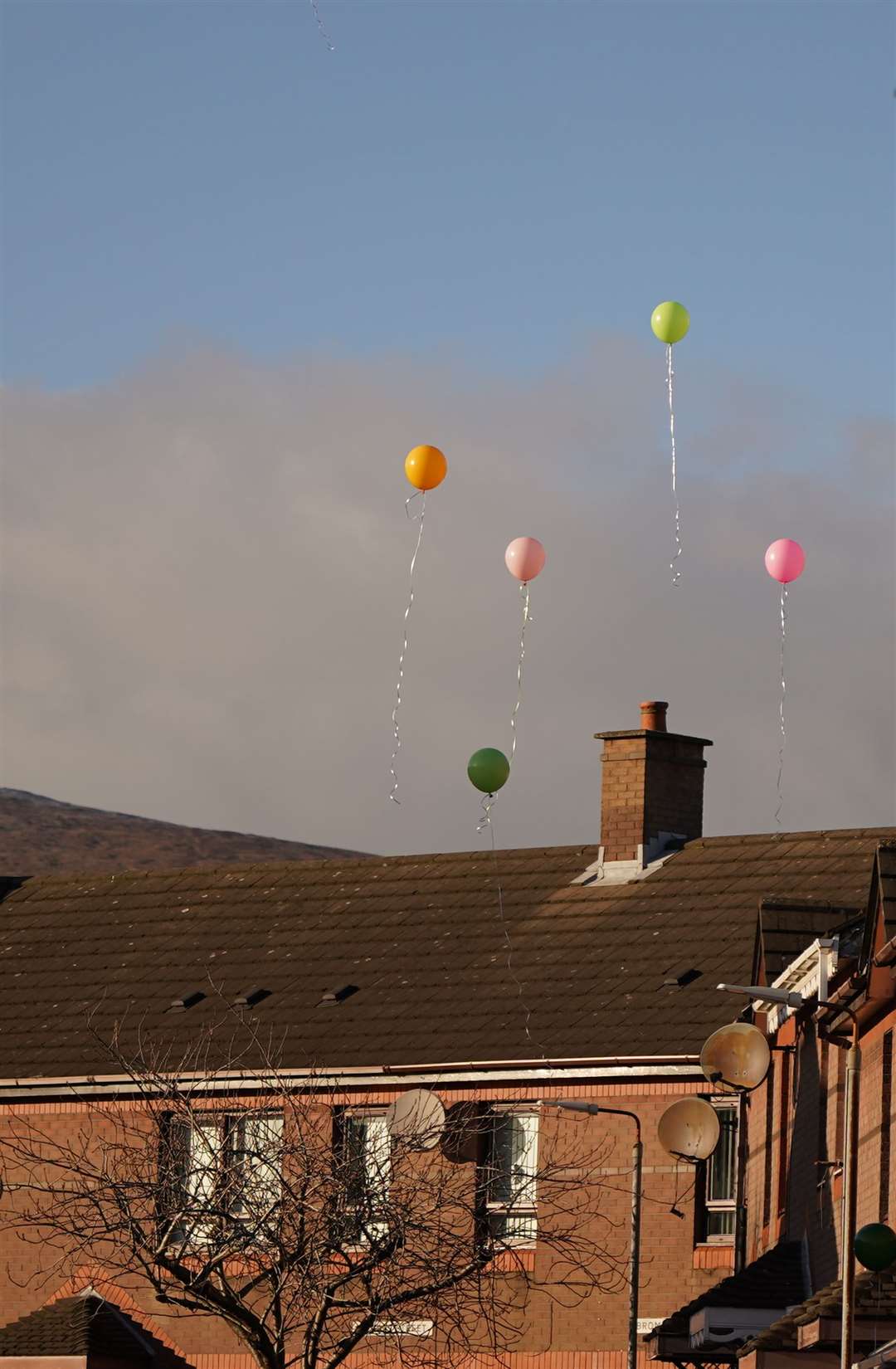 Mourners release brightly coloured helium balloons as the funeral cortege of Stella-Lily McCorkindale leaves the home of her grandmother in Belfast (Niall Carson/PA)